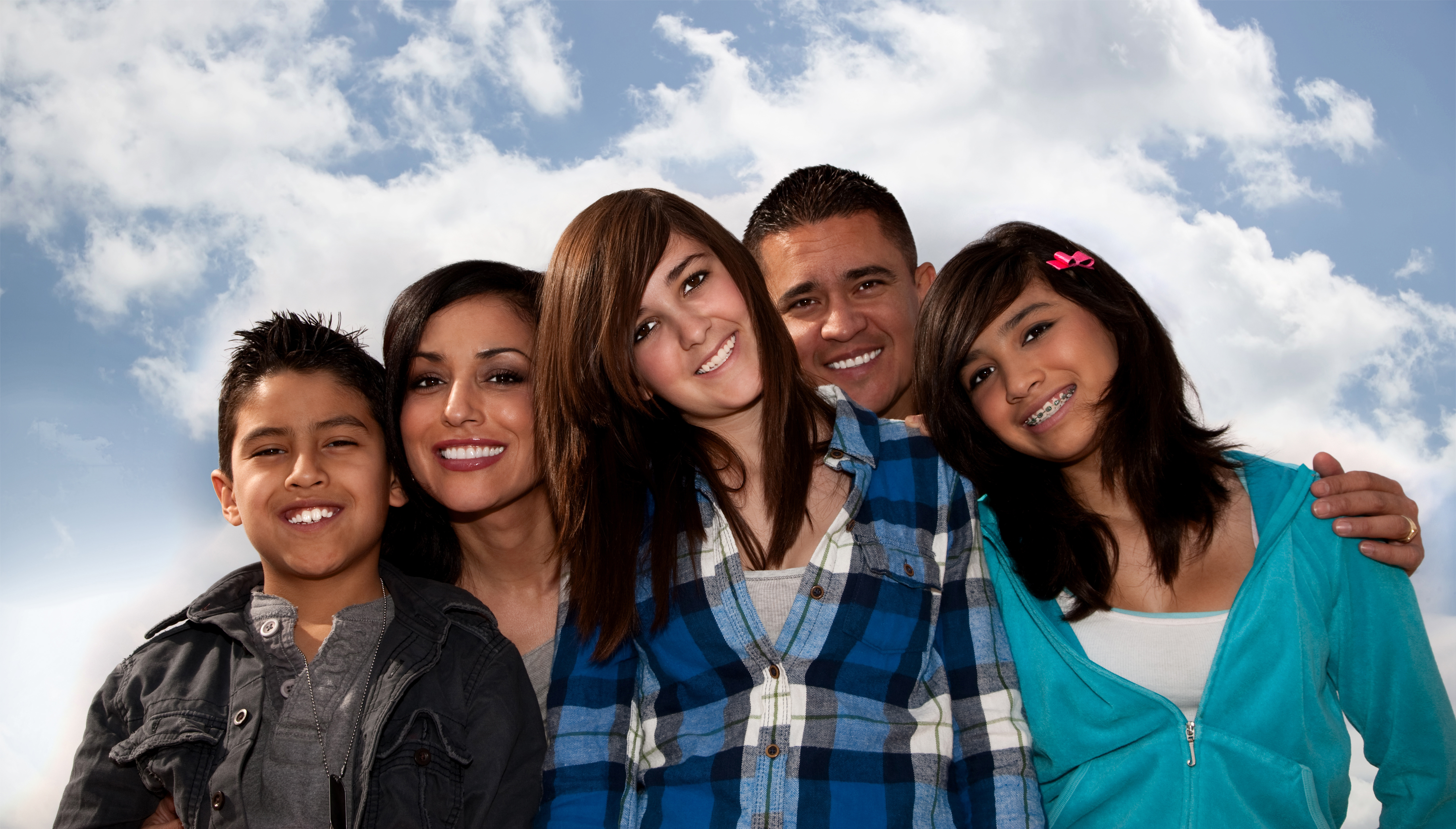 Hispanic family seated against a cloudy sky